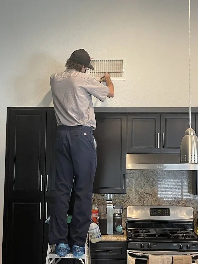 Technician inspecting an air vent during HVAC service in Starkville